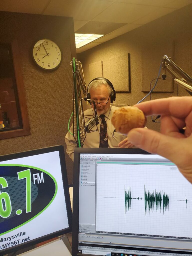 Mark Bingaman holding up a doughnut hole for the camera in studio at MY96.7 FM WDLR
